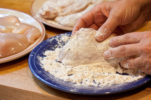 Press the flour into the chicken, but gently tap off the excess